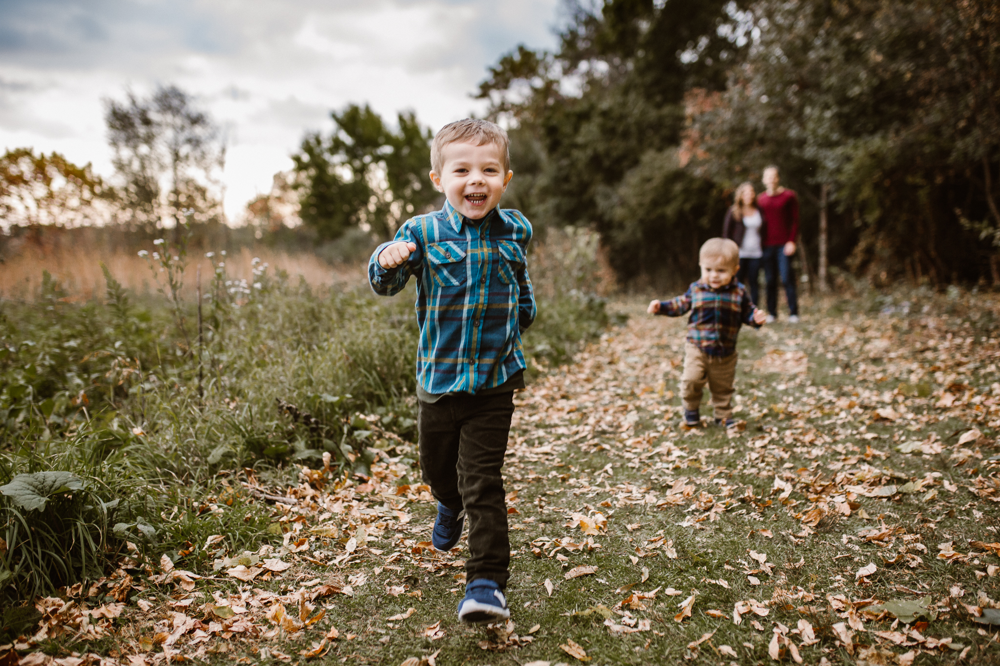 Two young brothers running free outside in the fall leaves.