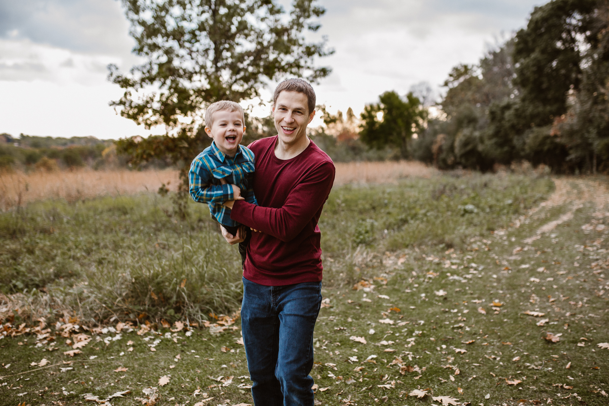 Father holding his son like an airplane at sunset.