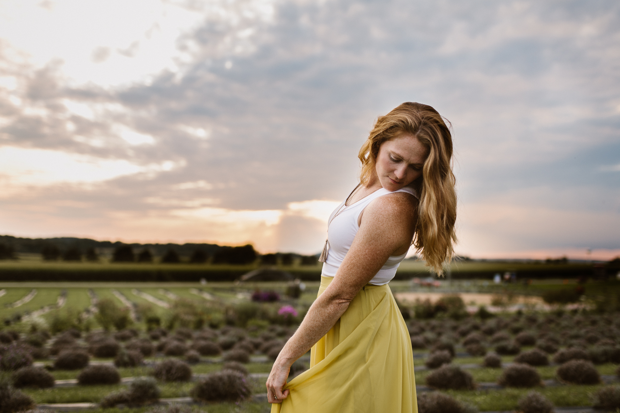 Red headed woman in yellow skirt at sunset in a lavender field.