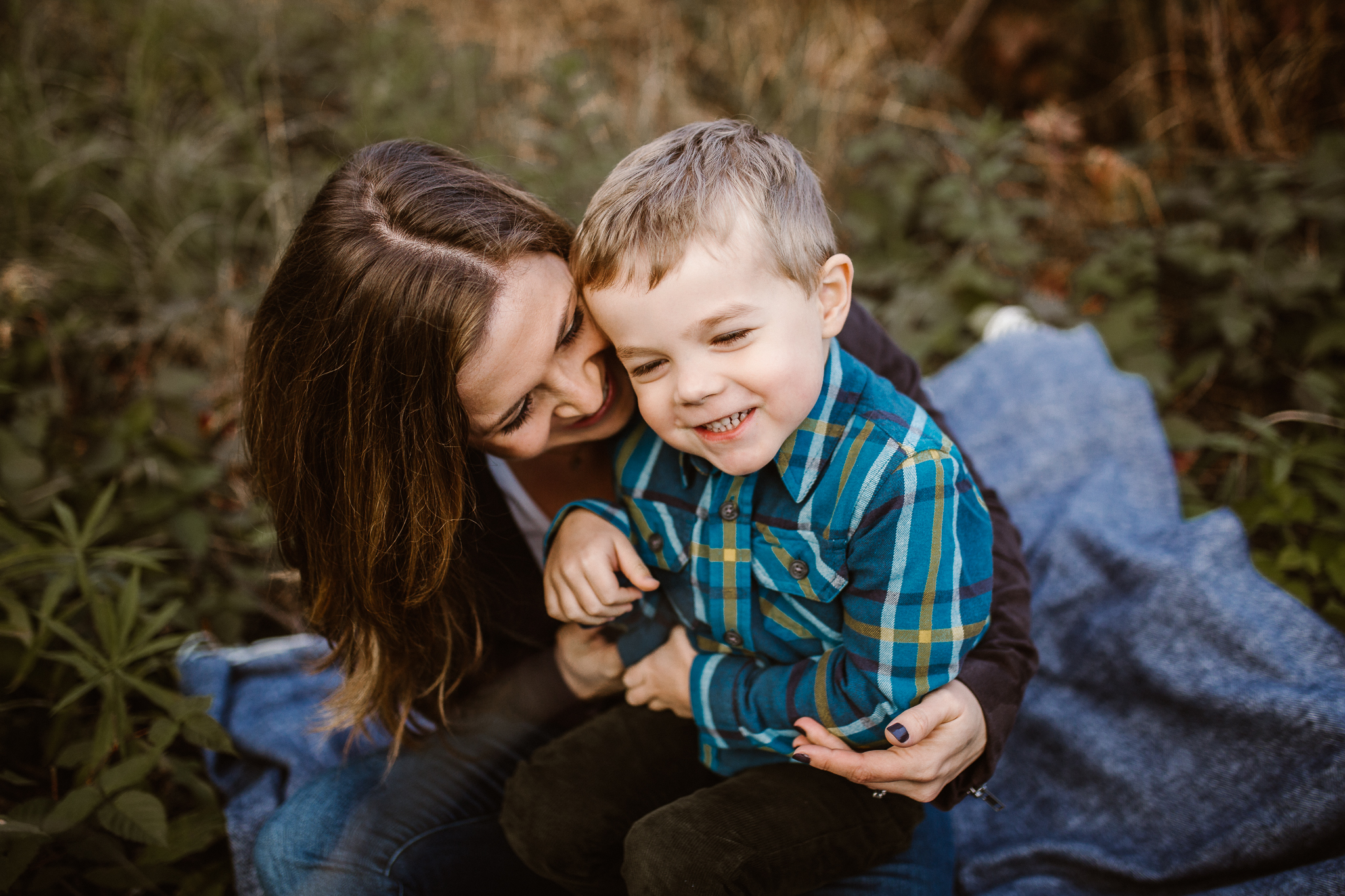 Mother holding her young son on her lap outside.