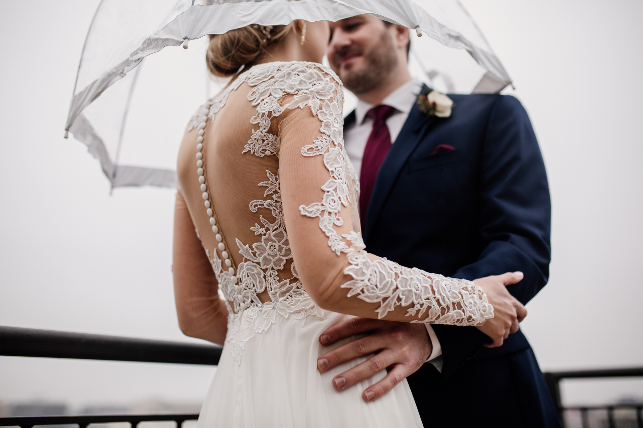 Bride and groom on the Edgewater Hotel balcony with an umbrella.