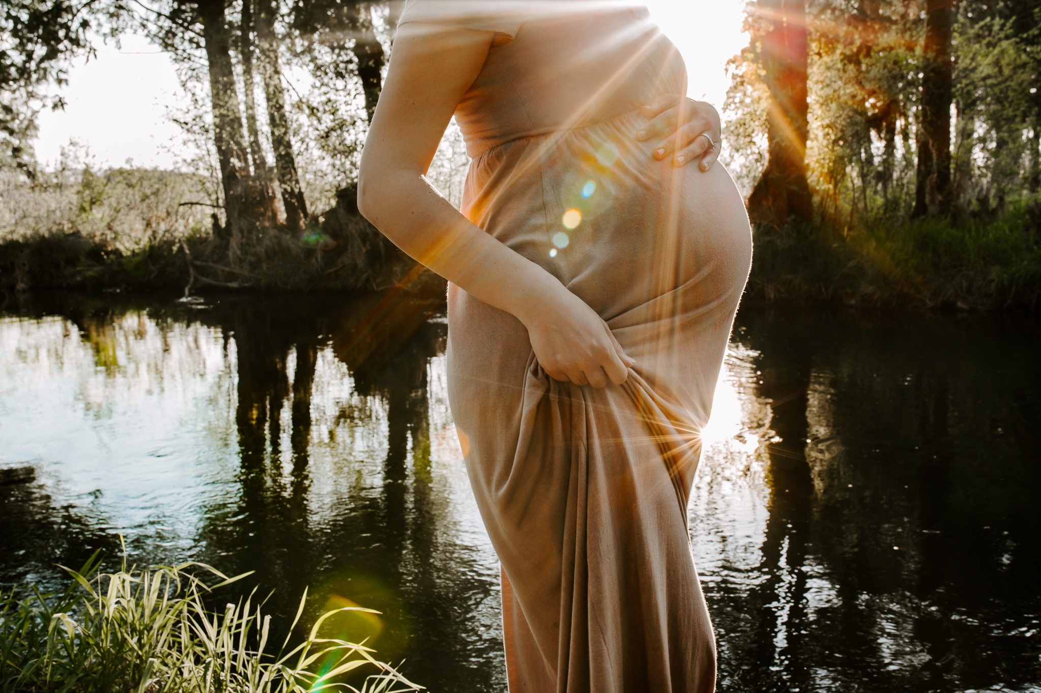 Expecting mother by a sun soaked creek druing golden hour.