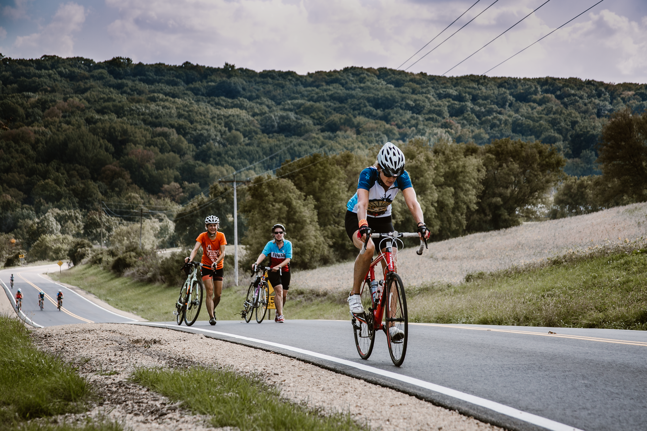 Women bicycling and walking up a steep hill in Wisconsin.