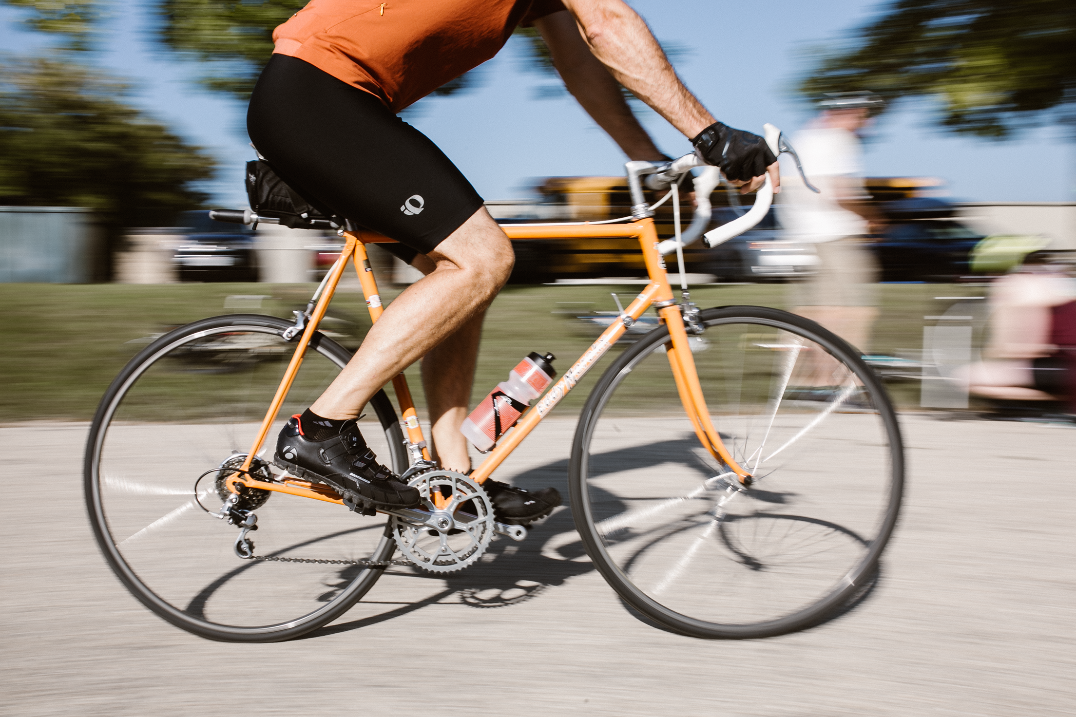 Cyclist on an orange bike racying by.