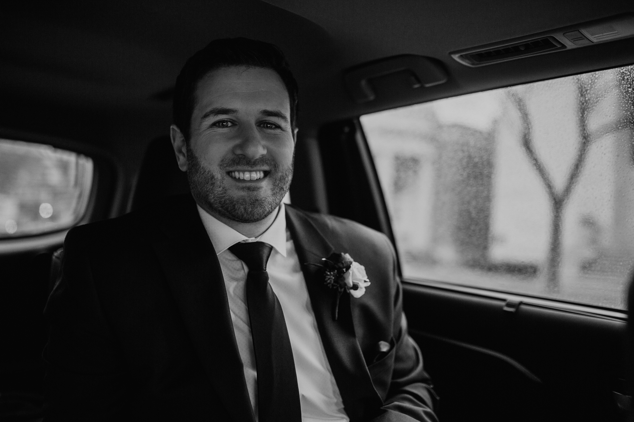 Groom smiling in the car on his way to the wedding ceremony.
