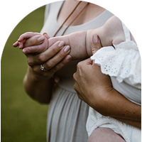 Mother holding her baby's arm. Baby has a grasp around mother's finger.