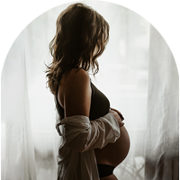 Pregnant mother standing in front of a bright window.